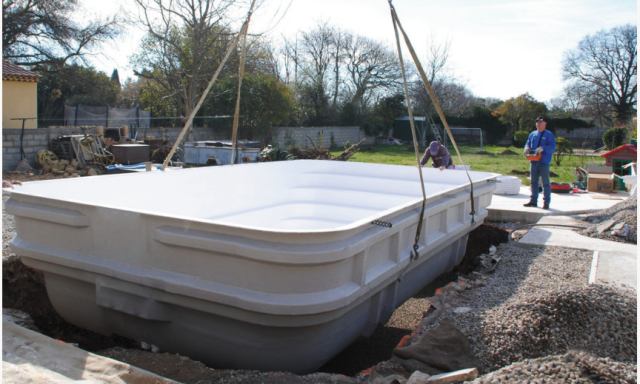 Descente d'une coque polyester par camion-grue dans la fouille